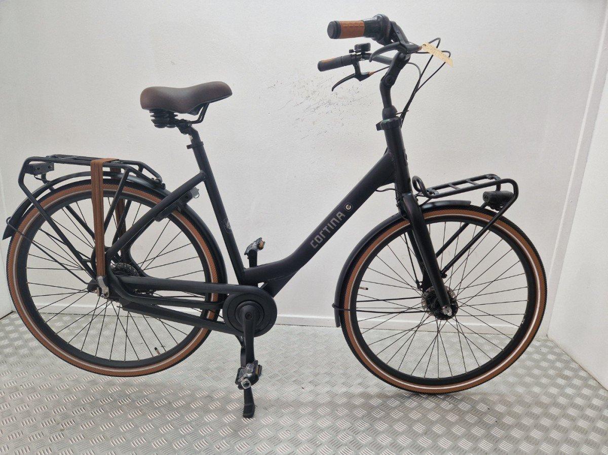 Cortina Comfort zwarte stadsfiets met lage instap, voordrager en dubbele standaard